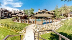 A resort with a pool, outdoor seating, and a pathway leading to the buildings. - Spacious newly renovated condo w/shared pools, hot tubs, & ski shuttle (Steamboat Springs)