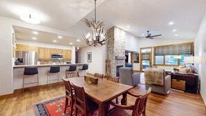 A spacious kitchen with a dining area, stone fireplace, and large windows. - Spacious newly renovated condo w/shared pools, hot tubs, & ski shuttle (Steamboat Springs)