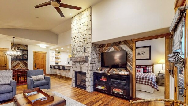 A spacious living area with a stone fireplace, a television, and a cozy seating arrangement. - Spacious newly renovated condo w/shared pools, hot tubs, & ski shuttle (Steamboat Springs)