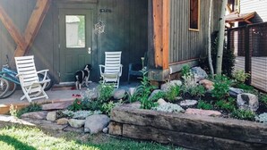 A wooden porch with two white chairs, a dog, and a bicycle. - Charming chalet with fireplace, loft & a true ski-in/out location (Telluride)