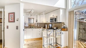 A modern kitchen with white cabinets, a stainless steel range, and a bar stool. - Charming chalet with fireplace, loft & a true ski-in/out location (Telluride)