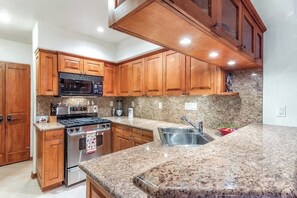 Eine Küche mit Holzausstattung, Granit Arbeitsplatten, Edelstahlgeräten und einer Granit-Spritzschutzwand.