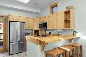 A modern kitchen with wooden cabinets, a stainless steel refrigerator, a microwave, and a gas stove. - Downtown condo with rooftop deck, mountain views & W/D - walk everywhere (Telluride)