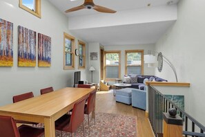 A spacious living area with a dining table, sofas, and artwork on the walls. - Downtown condo with rooftop deck, mountain views & W/D - walk everywhere (Telluride)
