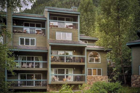 A multi-story building with balconies, outdoor seating, and a stone facade.