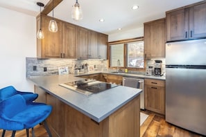 Eine moderne Küche mit Holzausstattung, einer großen Kochinsel mit Spüle und einem Edelstahlkühlschrank.