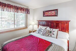 A bedroom with a bed, a window with blinds, a bedside table with a lamp, and a framed picture on the wall. - Mountain getaway with modern comforts- pool, hot tub & summer activities (Steamboat Springs)