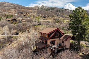 Ein zweistöckiges Haus mit Balkon, eingebettet in eine gebirgige Landschaft.