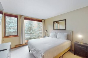 A bedroom with a bed, a bedside table, a nightstand, a window with curtains, and a mirror on the wall. - Vail-View Condo w/ Balcony, BBQ, Large Indoor Pool-Near Skiing (Vail)