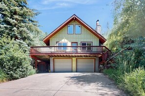 Ein zweigeschossiges Haus mit Garage, Balkon und Schornstein.