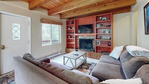 Een woonkamer met een houten plafond, een open haard, een televisie en een bank.