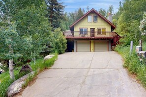 Ein zweistöckiges Haus mit Garage, umgeben von Grünflächen und einer Einfahrt mit Natursteinen.