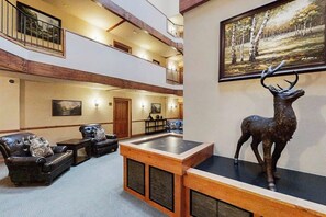 Eine geräumige Lobby mit hoher Decke, Kamin, Ledersofas und einer Hirschskulptur.
