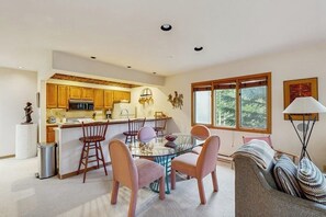 A modern kitchen with wooden cabinets, a glass dining table, and a cozy seating area with a couch and chairs. - Townsend Place ski-in/ski-out condo, two blocks to Beaver Creek Village (Beaver Creek)