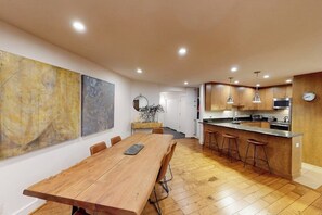 Eine moderne Küche mit Holztisch, Barhocker und einer großen Kochinsel.
