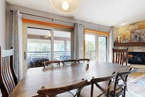 Ein Essbereich mit einem großen Holztisch und Stühlen, einem Kamin und großen Fenstern.