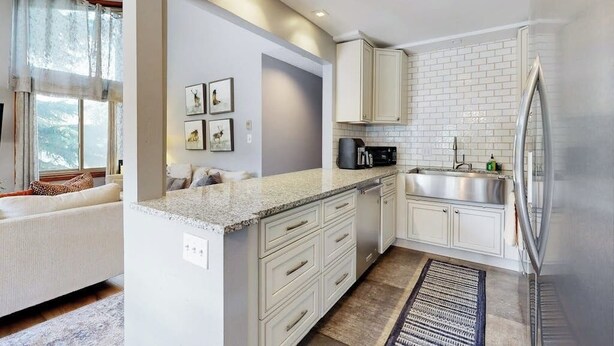 Una cocina moderna con armarios blancos, encimera de granito y electrodomésticos de acero inoxidable.