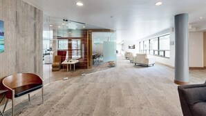A spacious lobby with a modern design, featuring a glass partition, a seating area with sofas and chairs, and a large pillar. - Vail Spa Condo w/ Pools, Hot Tubs & Gorgeous Valley Views - Near Lifts (Vail)
