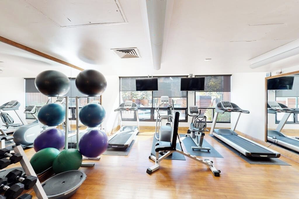 Un gimnasio con cintas de correr, elípticas y pelotas de ejercicio.