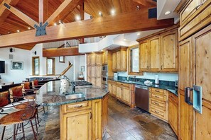 A spacious kitchen with wooden cabinets, a large island, and a stone floor. - Huge Multi-Level Home with Hot Tub, Separate Studio Apartment & Vail Views (Vail)