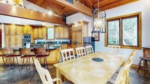 A spacious kitchen with wooden cabinets, a central island, and a dining area with a large table and chairs. - Huge Multi-Level Home with Hot Tub, Separate Studio Apartment & Vail Views (Vail)
