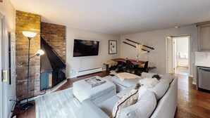 Een woonkamer met een open haard, een bank, een televisie en een eethoek.