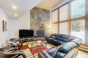 Ein modernes Wohnzimmer mit Flachbildfernseher, Ledersofa und einer Steinwand.