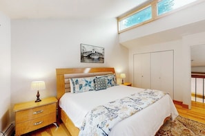 Ein Schlafzimmer mit Bett, Nachttischen, einem Wandbild und einem Kleiderschrank.