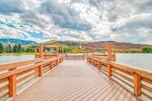 Un molo di legno che si estende verso un lago, con montagne sullo sfondo.