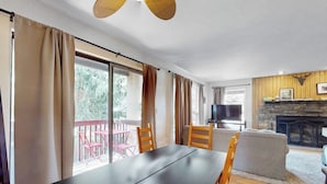 Um quarto com mesa de jantar, cadeiras, sofá, lareira e televisão.