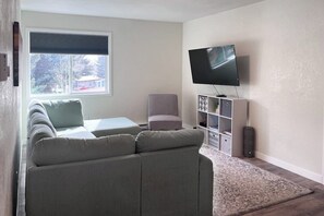 A living room with a sofa, a chair, a TV, and a bookshelf. - Remodeled mountain view condo with free WiFi and easy access to slopes (Avon)
