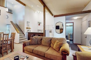 Ein Wohnzimmer mit einer Couch, einem Esstisch und einer Treppe.