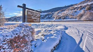 Letrero de Brookside Signature Lofts, Lodge y Townhomes, con un paisaje nevado al fondo.