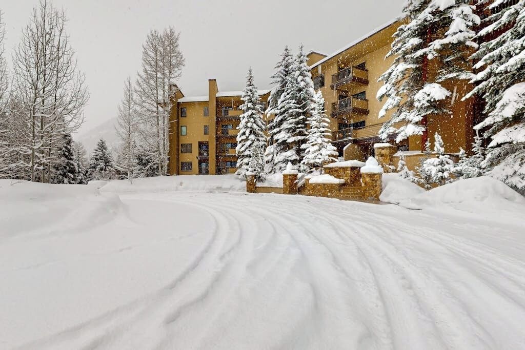 A snow-covered landscape with a building featuring multiple balconies and a ski slope.