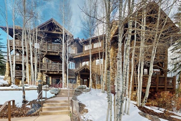 Ein mehrstöckiges Holzhaus, umgeben von Birken und Schnee.