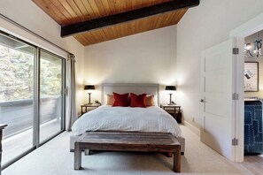 A bedroom with a large bed, wooden ceiling, and a bench. - Colorful Riverfront Chalet  with Shared Pool and Hot Tub - Close to Ski Slopes (Vail)