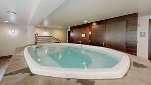 Ein Whirlpool in einem Raum mit schrägverdeckter Decke, Holzwandverkleidung und Fliesenboden.