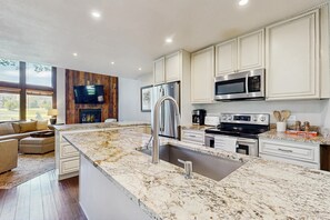 Eine moderne Küche mit Granit-Arbeitsplatten, Edelstahlgeräten und einer großen Kochinsel mit Spüle.