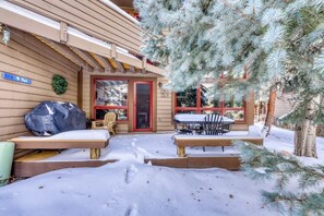 Ein Holzhaus mit überdachter Terrasse, Außenbestuhlung und verschneitem Gelände.
