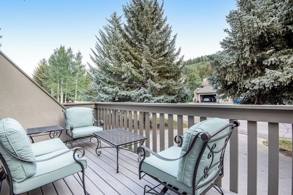 A deck with outdoor furniture, a pergola, and a view of snow-covered trees.