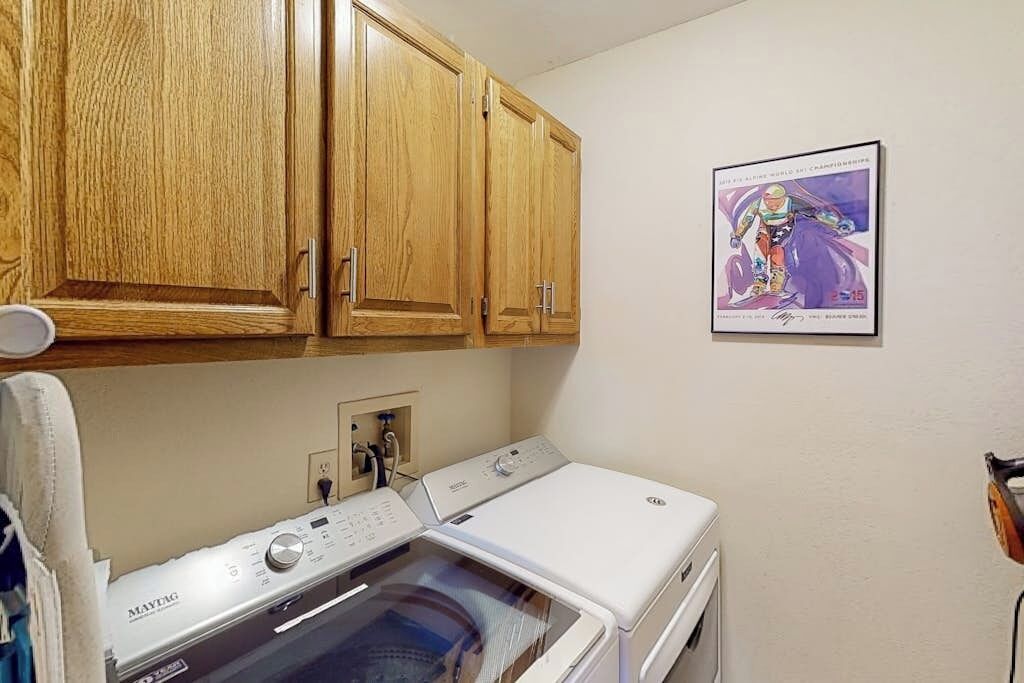Une buanderie avec des armoires en bois, un lave-linge Maytag et une affiche accrochée au mur.