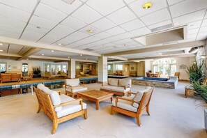 Eine großzügige Lobby mit Pool, Holzmöbeln und Blick auf den Poolbereich.