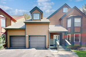 Ein Wohngebäude mit zwei Garagentoren, einer Veranda und einem kleinen Anbau als Garage.