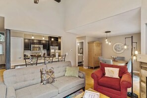 Ein Wohnzimmer mit grauem Sofa, einem roten Sessel und einem Essbereich mit Tisch und Stühlen.