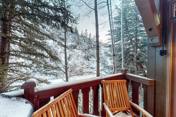 Eine Holzterrasse mit Stühlen, umgeben von schneebedeckten Bäumen.