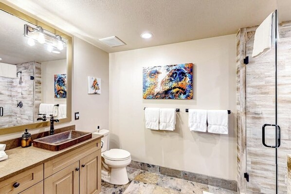 A modern bathroom with a large mirror, a rectangular sink, a toilet, and a shower area. - Slope-side condo next to the Arrow Bahn Express, with mountain-view balcony (Edwards)