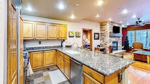A kitchen with wooden cabinets, granite countertops, a built-in stove, and a dining area with a fireplace.