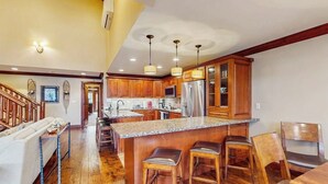 Una cocina amplia con armarios de madera, encimera de granito y una isla central con taburetes de bar.