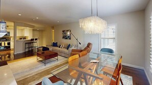 Ein modernes Wohnzimmer mit einem Glastisch, einer Couch und einer Pendelleuchte.