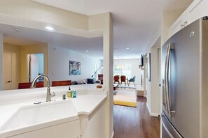 Eine moderne Küche mit einem Edelstahl-Kühlschrank, einer weißen Arbeitsplatte und einem Spülbecken.